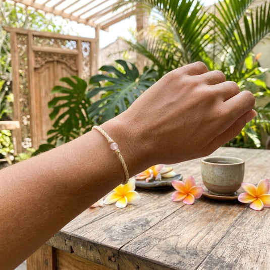 Rose quartz Bali intention bracelet worn in a tropical garden setting