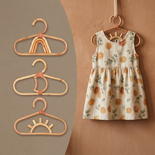 Bamboo kids hanger set with playful rainbow and sun designs in a warm nursery setting