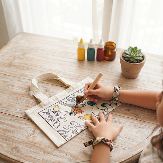 Child painting a Bali shell design on a batik tote bag craft project