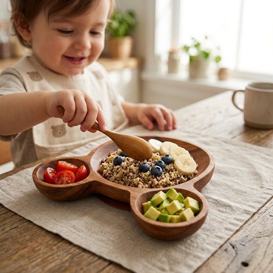 Child using a wooden bear-shaped mealtime plate with divided sections for fruit and grains
