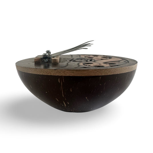 Side view of a handcrafted coconut shell kalimba with metal keys and an engraved wooden top in the Island Flow design