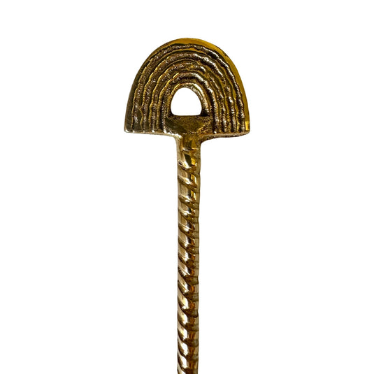 Close-up of brass ritual tea spoon with rainbow arch handle