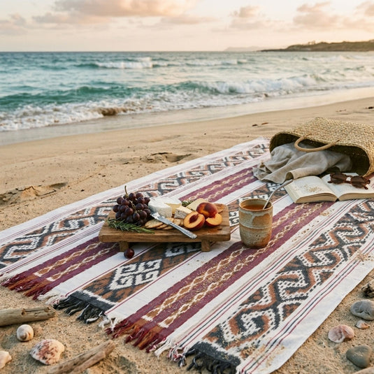 Handwoven ikat blanket in the Sunwashed Sand pattern styled for a beach picnic