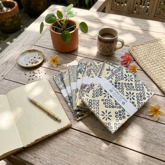 Plantable batik notebooks with traditional blue patterns displayed on a wooden table in a relaxed Bali setting